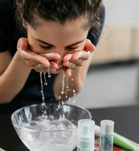 Osoba se umiva nad posudom s vodom