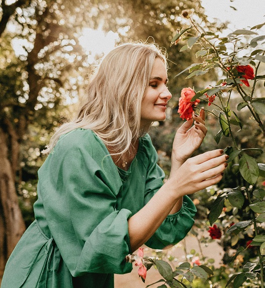 Žena uživa u mirisu cveća