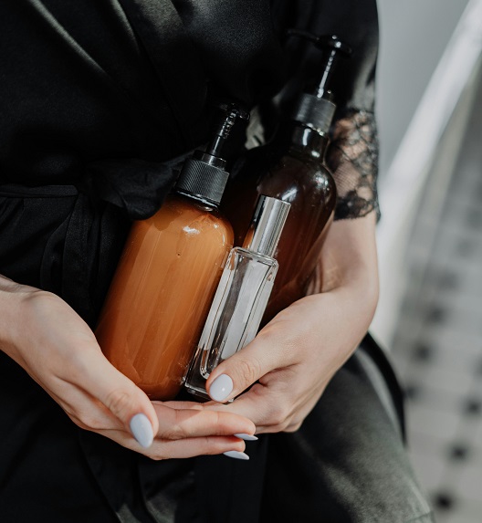 A woman in a black robe holds bottles containing medical grade products.