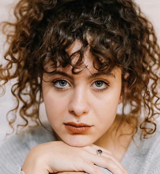 Devojka sa kovrdžama razmišlja kako koža reaguje na manjak sunca i vitamina D