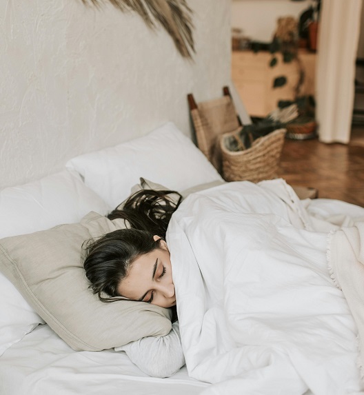 A woman sleeps peacefully on her side in a comfortable bed.