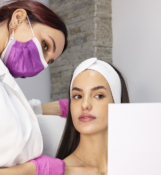 devojka se ogleda u ogledalu nakon tretmana lica