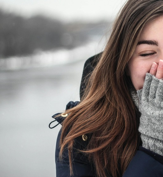 mlada žena na hladnom vazduhu pored zaleđenog jezera