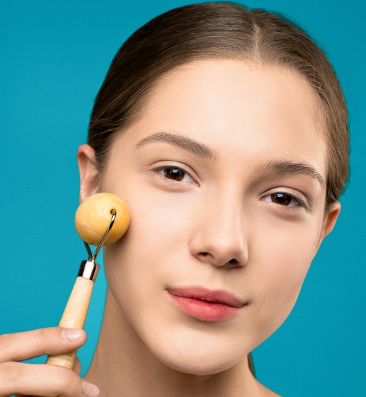 devojka koristi roler za masažu lica kod kuće.