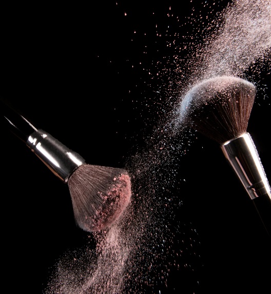 Makeup brushes with scattered powder on a black background.